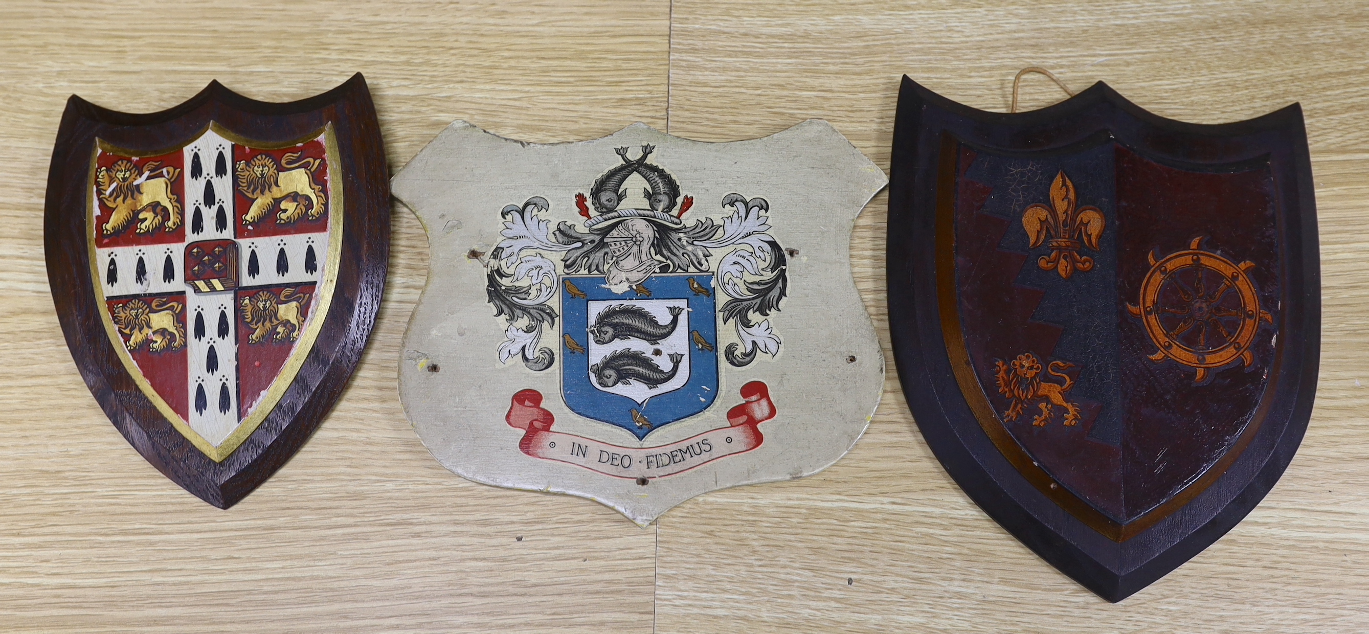 Three heraldic armorial shield shaped crests, one with Latin motto, In Deo Fidemus, the largest 24cm high